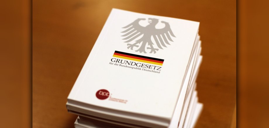 Stapel mit der gedruckten Version des Deutschen Grundgesetzes auf Tischplatte aus Holz